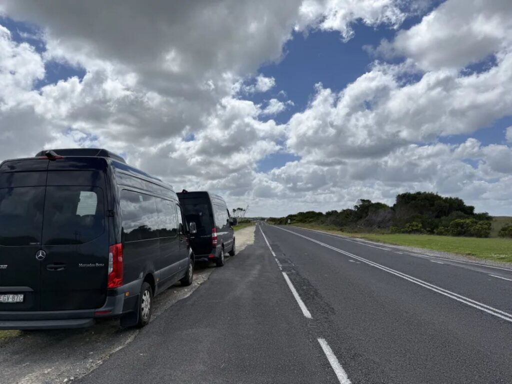 两辆奔驰商务车停靠在开阔的澳洲公路旁，东西大穿越自驾车队休整