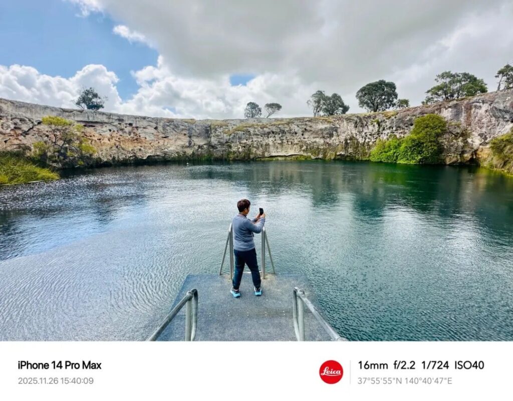游客在小蓝湖平台上用手机拍摄火山湖，南澳旅行摄影打卡点