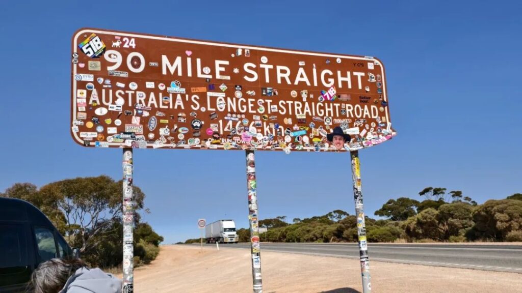 90 Mile Straight路牌与远处公路火车