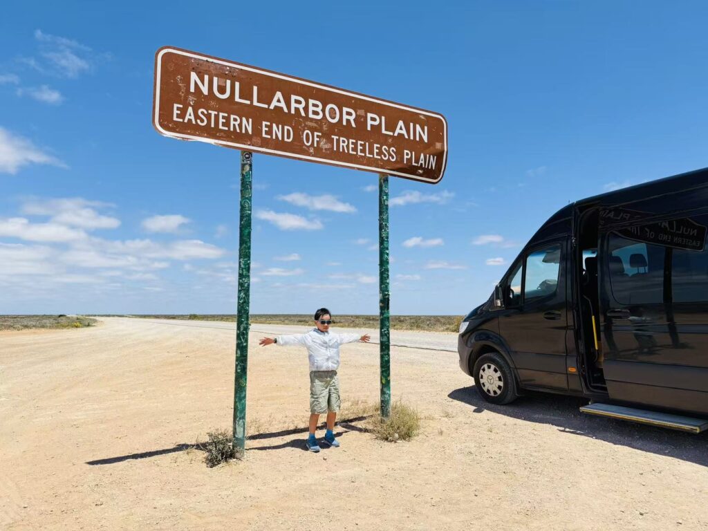 小男孩在Nullarbor Plain路牌下张开双臂
